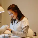 Ann-Sophie die manicure toedient bij een klant.